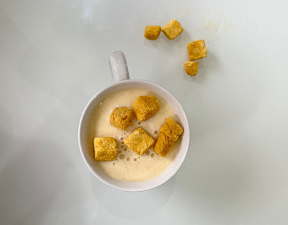 Bowl of cereal with gold-colored cereal pieces on a white background